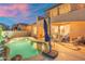 Backyard pool with rock waterfall and outdoor seating area, under a colorful sunset at 8432 S 21St Pl, Phoenix, AZ 85042