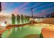 Backyard pool featuring a rock waterfall and lush landscaping, illuminated at dusk at 8432 S 21St Pl, Phoenix, AZ 85042