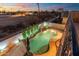 Elevated view of a backyard pool with a rock waterfall, lush greenery, and sunset sky at 8432 S 21St Pl, Phoenix, AZ 85042