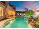 Backyard pool with rock waterfall, an outdoor kitchen, and mountain views at dusk at 8432 S 21St Pl, Phoenix, AZ 85042