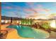 Backyard pool with rock waterfall feature, surrounded by lush landscaping, and an outdoor kitchen at 8432 S 21St Pl, Phoenix, AZ 85042