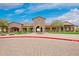 Beautiful clubhouse exterior featuring a central archway, lush landscaping, and stone architecture at 9041 E Ivyglen Cir, Mesa, AZ 85207