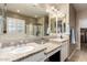 Bathroom featuring dual sinks with granite counters, neutral color palette, and a glass enclosed shower at 9286 W Buckhorn Trl, Peoria, AZ 85383