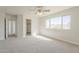 A bright bedroom featuring carpet, a ceiling fan, and a large window with neighborhood views at 9939 W Southgate Ave, Tolleson, AZ 85353