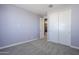 Bedroom with light-colored walls, neutral carpet, closet and view into the adjacent room at 10013 E Trent Ave, Mesa, AZ 85212