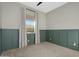 Bedroom with paneled green walls, neutral carpet, and a bright window at 10144 E Thistle Ave, Mesa, AZ 85212