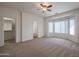 Bedroom with neutral carpet, ceiling fan, bay window, walk-in closet, and an ensuite bathroom at 11725 W Jefferson St, Avondale, AZ 85323