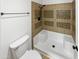 Tiled bathtub and shower combination with dark fixtures and a white toilet at 1810 W Kiowa Cir, Mesa, AZ 85202