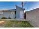 Enclosed backyard with a block wall, grass, and a blue shed with a white door, all under a clear blue sky at 1822 N Laurel Ave, Phoenix, AZ 85007