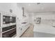 Modern white kitchen featuring stainless steel appliances, a large island, and sleek black hardware at 20261 W Monterey Way, Buckeye, AZ 85396