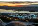 Aerial view of a resort-style pool and splash pad with evening lights and a stunning sunset backdrop at 23102 E Raven Dr, Queen Creek, AZ 85142