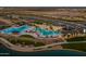 Stunning aerial view of a community pool area with palm trees, shade structures, and inviting lounge areas at 23102 E Raven Dr, Queen Creek, AZ 85142