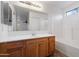 Bathroom with oak vanity, a shower and tub combo, and white walls at 2323 W Carson Rd, Phoenix, AZ 85041