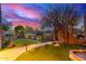 Landscaped backyard with a stone walkway, lush lawn, archway, and vibrant sunset at 30600 N Pima Rd # 49, Scottsdale, AZ 85266