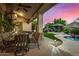 Covered outdoor patio with dining area, stone columns, and views of the pool and landscaped backyard at 11336 N 117Th Way, Scottsdale, AZ 85259