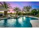 Scenic pool area featuring a rock waterfall, palm trees, and comfortable seating, perfect for relaxing evenings at 11336 N 117Th Way, Scottsdale, AZ 85259