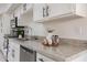 Close-up of a kitchen counter featuring stone countertops, white cabinets and stainless steel appliances at 19305 N 78Th Ave, Glendale, AZ 85308