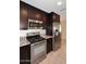 Lovely kitchen with stainless steel microwave, gas range, refrigerator and granite countertops, tiled floors and dark wood cabinets at 1966 E Pebble Beach Dr, Tempe, AZ 85282