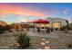 This backyard features a patio with an umbrella and seating, surrounded by desert landscaping at sunset at 20331 N Wagner Wash Dr, Buckeye, AZ 85396