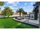 Landscaped backyard with a fire pit, lush grass, and mature trees providing a serene outdoor space at 2818 E Malapai Dr, Phoenix, AZ 85028
