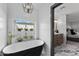 Beautiful primary bathroom featuring black and white bathtub, textured walls, and elegant light fixture at 2818 E Malapai Dr, Phoenix, AZ 85028