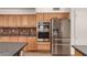 The kitchen features wood cabinetry, brick accent, stainless appliances, and granite countertops at 333 N Pennington Dr # 63, Chandler, AZ 85224