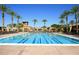 Gorgeous community pool and recreation center area with clear blue water and lounge seating surrounded by palm trees at 4297 E Pyrenees Ct, Gilbert, AZ 85298