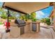 Outdoor kitchen and grill with built in countertops and mini fridge in brick backyard at 4297 E Pyrenees Ct, Gilbert, AZ 85298