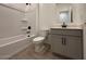 Well-lit bathroom featuring a tub, shower combination and a vanity with a gray cabinet and wood-look tile floors at 47734 W Moeller Rd, Maricopa, AZ 85139