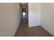 Long hallway featuring stylish wood-look tile flooring, bright lighting, and smooth white walls, providing a modern feel at 47734 W Moeller Rd, Maricopa, AZ 85139