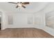 A spacious bedroom with wood floors, three windows with blinds, and a ceiling fan at 654 W Natal Cir, Mesa, AZ 85210