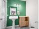 Stylish bathroom featuring a white pedestal sink against a bold green wall and modern fixtures at 7726 W Cameron Dr, Peoria, AZ 85345