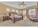 Luxurious main bedroom with an ornate bed frame, ceiling fan, sitting area, and carpet flooring at 9626 W Bajada Rd, Peoria, AZ 85383
