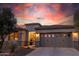 Exterior view of single-story home with decorative garage windows illuminated against a vibrant sunset sky at 13068 W Mine Trl, Peoria, AZ 85383