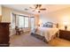 Bright main bedroom with bay windows, ceiling fan and large bed with decorative pillows at 13068 W Mine Trl, Peoria, AZ 85383
