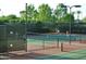 Outdoor tennis courts with players in action, surrounded by trees and a secure fence at 13068 W Mine Trl, Peoria, AZ 85383