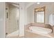 Elegant bathroom with a glass shower, soaking tub, and decorative gold-framed mirror at 15802 N 71St St # 311, Scottsdale, AZ 85254