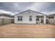Unfinished backyard showcases the home's stucco exterior, gray trim windows, and spacious layout at 17567 W Adams St, Goodyear, AZ 85338