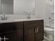 Bathroom with a double sink vanity featuring dark wood cabinets, white countertops, and shower at 17567 W Adams St, Goodyear, AZ 85338