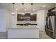 Bright kitchen featuring a large island, pendant lighting, stainless steel refrigerator, and dark wood cabinetry at 17567 W Adams St, Goodyear, AZ 85338