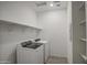 Bright laundry room featuring a washer, dryer, storage shelves, and light wood-look flooring at 17567 W Adams St, Goodyear, AZ 85338