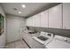 Well-lit laundry room with modern washer and dryer, utility sink, and plenty of storage cabinets at 19700 N 76Th St # 1124, Scottsdale, AZ 85255