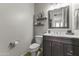Neutral powder room featuring a dark vanity, marble countertop, framed mirror, and classic fixtures at 20897 W Edith Way, Buckeye, AZ 85396
