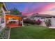 Beautiful backyard featuring a covered patio with string lights, artificial turf, and lush landscaping at 2321 N Glenview --, Mesa, AZ 85213