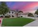 Charming single-Gathering home featuring a manicured front yard with three-car garage under a colorful evening sky at 2321 N Glenview --, Mesa, AZ 85213