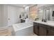 Bathroom featuring a soaking tub, double vanities, large mirrors, and a garden window for natural light at 24626 N 143Rd Dr, Surprise, AZ 85387