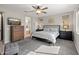 Neutral-toned bedroom featuring a king bed, ceiling fan, gray carpet, flat screen television and ensuite bath access at 24626 N 143Rd Dr, Surprise, AZ 85387