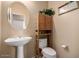 Charming powder room with pedestal sink and decorative storage cabinet with a toilet at 3285 E Phelps St, Gilbert, AZ 85295