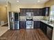 Modern kitchen with stainless steel appliances, dark cabinets, granite countertops, and wood floors at 36905 W Mattino Ln, Maricopa, AZ 85138