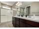 Bathroom featuring double sinks, dark wood cabinets, and a tiled shower at 37783 W San Sisto Ave, Maricopa, AZ 85138